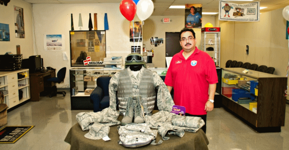 A picture of an employee standing next to a display of tactical gear.