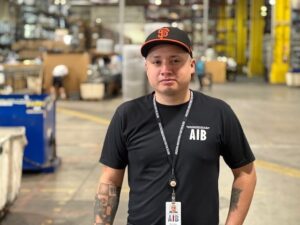 Photograph of AIB Employee, Rick Veloz, standing in the DSU Warehouse.