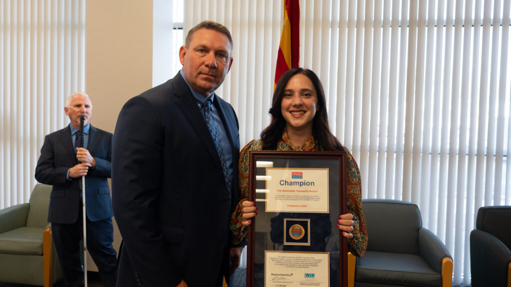 Arizona Industries for the Blind President and CEO Chris LaFollettte stands besides Representative Yassamin Ansari as she holds the framed AbilityOne Congressional Champion Award, presented on September 10, 2026 at AIB headquarter. The award recognizes Rep. Ansari’s commitment to improving the lives of Americans who are blind or have significant disabilities and her support of the AbilityOne Program. David Steinmetz, AIB Public Policy Manager, stands behind them.
